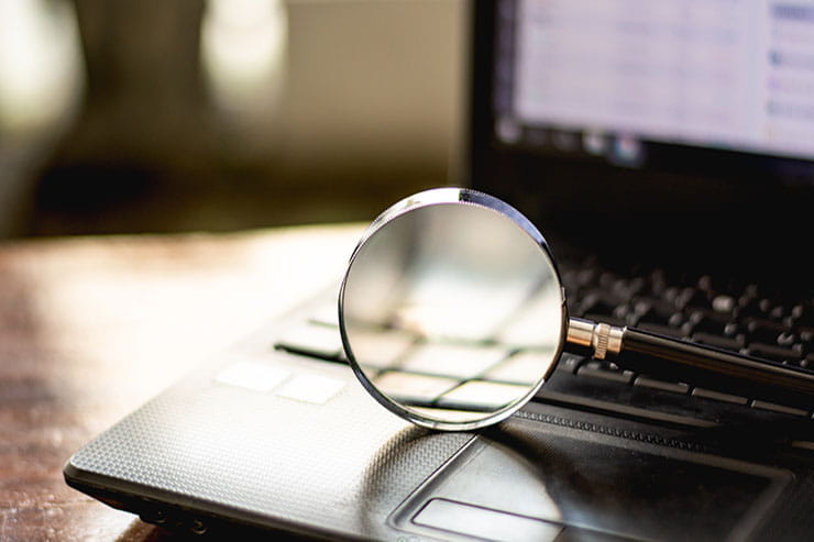 Picture of a magnifying glass on a laptop keyboard. 
