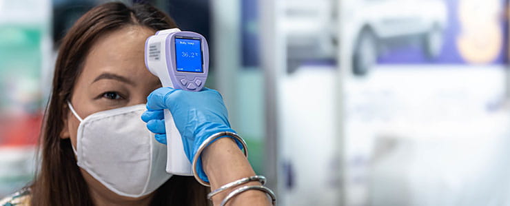 Woman having temperature scanned: health screener model