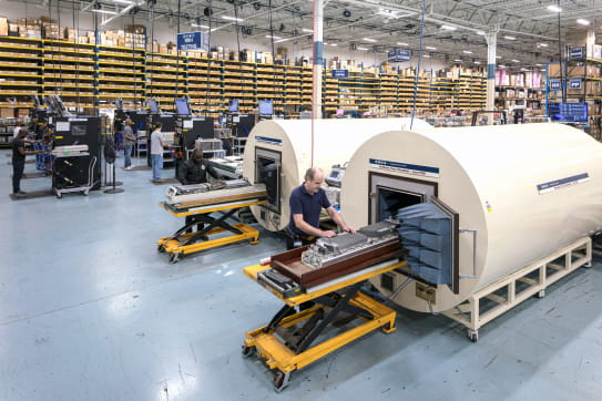 Employees assemble machines in a warehouse